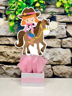 a paper cutout of a girl riding a horse on top of a pink box