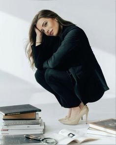 a woman kneeling down next to some books