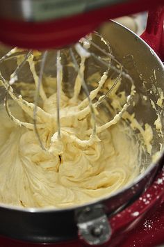 a red mixer filled with yellow batter on top of a counter