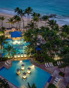 an aerial view of the pool and beach at night, with palm trees in the foreground