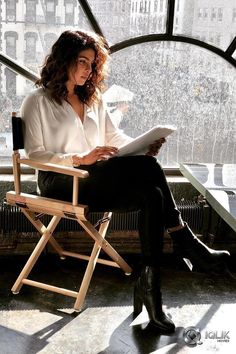 a woman sitting in a chair looking at something on her lap while holding a piece of paper