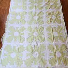 a green and white quilt sitting on top of a wooden floor