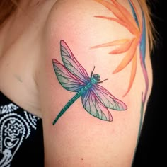 a woman's arm with a dragonfly tattoo on the left side of her shoulder