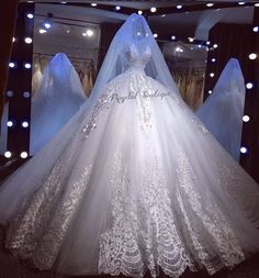 a white wedding dress is on display in front of a mirror with lights around it