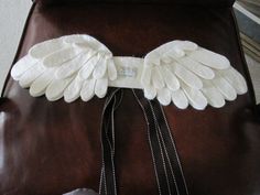 an angel wing is attached to the back of a brown leather chair with beads on it