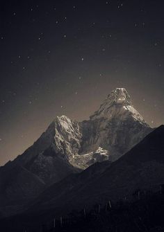 black and white photograph of the mountains at night with stars in the sky over them