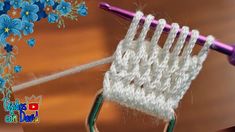 a close up of a crochet basket on a table with flowers in the background