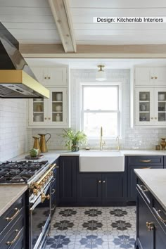 a kitchen with blue cabinets and white counter tops, gold accents on the windowsill