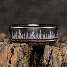 a ring with trees on it sitting on top of a tree stump in front of a dark background