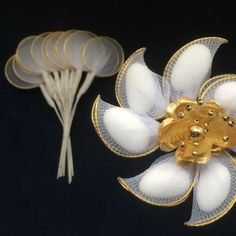 two white and gold flower shaped objects next to each other