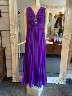 "Stunning purple pleated maxi dress with a fabulous beaded appliqué just under the neckline. The cut of the waist is a touch higher and is very flattering, giving it a bit of a princess cut/vibe. The skirt has quite a bit of fabric and moves beautifully as you walk or dance!  Lined. Does up with a zipper down the back. Condition: Great - there is a hook and eye on the back, at the top of the zipper- the \"eye\" portion is no longer there. Label: a Melody dress Fabric Content: no fabric label, but is likely polyester and acetate Size on Label: none Measurements: Shoulder to shoulder: approx 15\" Bust: 38\" Waist: 30\" Hip: 42\" Length: 56.5\"  Arm Opening: 15\" *IMPORTANT NOTE: All measurements are taken with the garment lying flat and then doubled. Please leave some wiggle room for comfort Party Floor-length Maxi Dress With Pleated Waist, Formal Pleated Maxi Dress For Prom Season, Party Maxi Dress With Pleated Waist, Pleated Maxi Dress For Prom Gala, Pleated Maxi Dress For Prom Season, Pleated Maxi Dress For Gala Prom Season, Purple Sleeveless Maxi Dress For Prom Season, Purple Sleeveless Maxi Dress For Prom, Elegant Pleated Maxi Dress For Prom