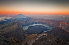 an aerial view of the mountains and lakes at sunset, with a moon in the distance