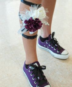 a woman's legs with purple and white flowers tied to their ankles while standing on the floor