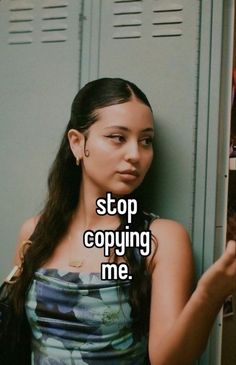 a woman leaning against a locker with the words stop copying me on her chest and looking at the camera