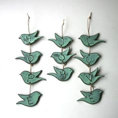 several green birds hanging from strings on a white wall