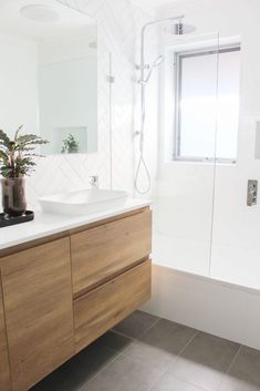 a bathroom with a sink, mirror and bathtub next to a shower head mounted on the wall