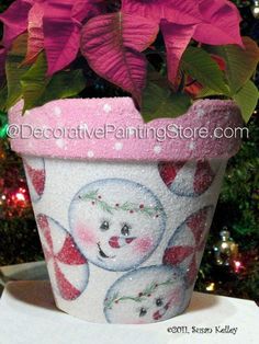 the potted plant is decorated with pink poinsettias and candy canes