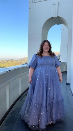 a woman in a blue dress standing on a balcony