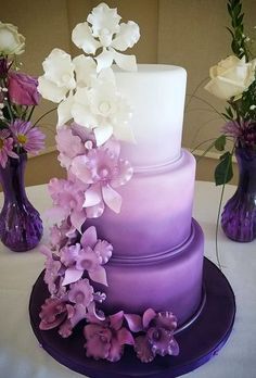 a three tiered cake with purple and white flowers