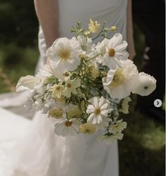 a bride holding a bouquet of white and yellow flowers