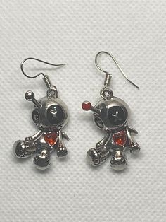 These Tibetan silver charms are adorable vodo dolls, kinda slouchy, black button eyes with x stitches.  They both have red crystal hearts. Bith have pins in their head, one pin has a red head on the pin.  The other earring the pin does not have red on.  the ear wires I added are nickel free surgical steel  All  materials used are nickel free. Please feel free to reach out with any questions. I ship daily Mon-Fri except holiday, with tracking in USA only  PLEASE NOTE: local regulations do not allow returns or exchanges of pierced jewelry. Emo Metal Earrings For Gift, Emo Style Metal Earrings For Gift, Nickel Free Silver Emo Earrings, Nickel-free Silver Emo Earrings, Silver Nickel-free Emo Earrings, Nickel-free Emo Earrings For Gift, Vodo Dolls, Emo Earrings, Doll Earrings