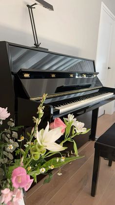 a black piano with flowers in the foreground