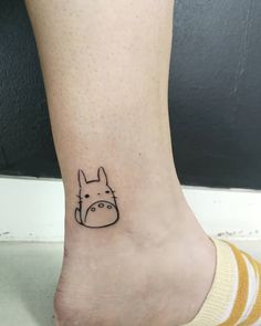 a small tattoo on the ankle of a person with a dog face drawn on it