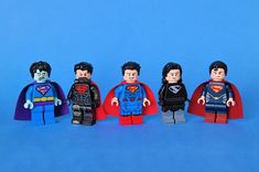 five lego supermans standing in a row on a blue background