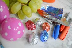 some candy and grapes are sitting on a marble counter top next to a pair of scissors