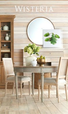 a dining room table with chairs and vases on it, in front of a wood paneled wall