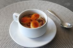 a white bowl filled with food on top of a saucer next to a spoon