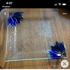 two blue flowers sitting on top of a wooden table next to a plastic container filled with water