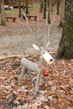 a statue of a deer is in the middle of leaves on the ground next to a tree