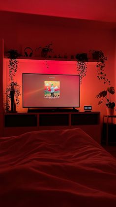 a flat screen tv sitting on top of a wooden entertainment center under a red light