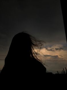 the silhouette of a woman with her hair blowing in the wind