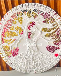 a decorative paper plate with a tree on the front and bottom, decorated with colorful leaves