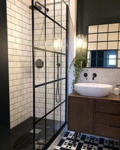 a black and white tiled bathroom with a walk in shower next to a vanity sink