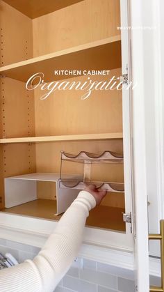 a woman is opening the door to a kitchen cabinet organization unit with drawers and shelves