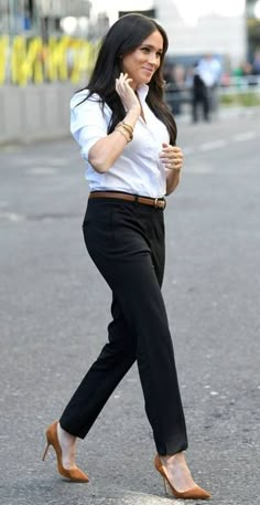 a woman is walking down the street talking on her cell phone while wearing high heels