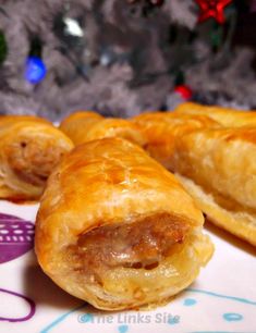 two sausage rolls on a plate next to a christmas tree