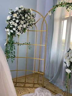 a white flower arrangement on a gold stand next to a bride's wedding dress