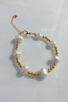 a bracelet with pearls and gold beads on a white tablecloth, featuring the name made love