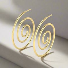 a pair of gold spiral earrings sitting on top of a white surface