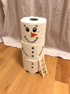 a toilet paper roll with a snowman face on it sitting on a wooden floor