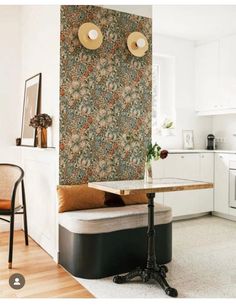 a kitchen area with a table, chairs and a wallpapered background on the wall