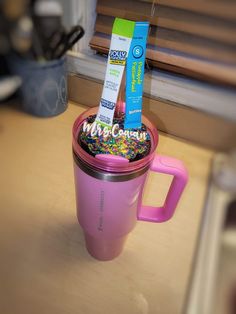 a pink coffee cup with sprinkles and toothpaste in it sitting on a counter