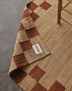 a brown and white rug with a tag on it next to a wooden chair in the background