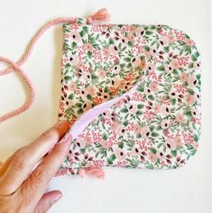 someone is sewing on the side of a piece of fabric with pink and green flowers