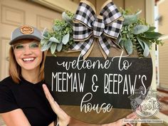 a woman holding up a sign that says welcome to meena and beraw's house