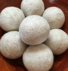 several balls of wool sit in a bowl on a wooden table, ready to be used as decorations